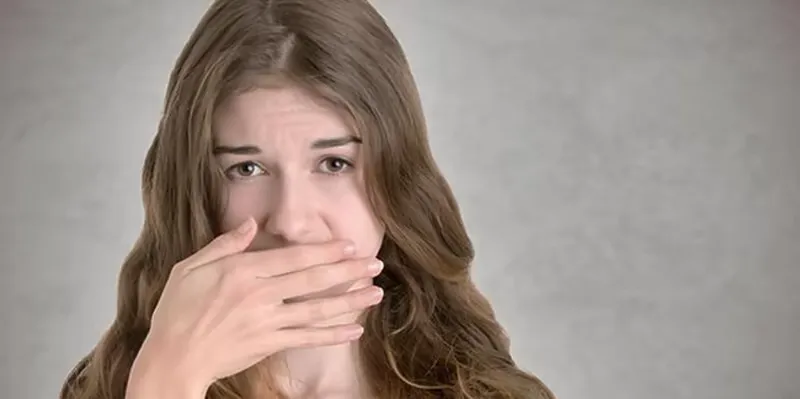 Frau hält die Hand vor den Mund wegen üblem Geruch